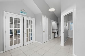 A hallway with two white doors, a laundry area with a washing machine, and a hanging sign that reads 'Just Another Day in Paradise.' - Pet-Friendly 5BR Retreat w/ 2 Kitchens + Sleeps 13 (Port Orange)