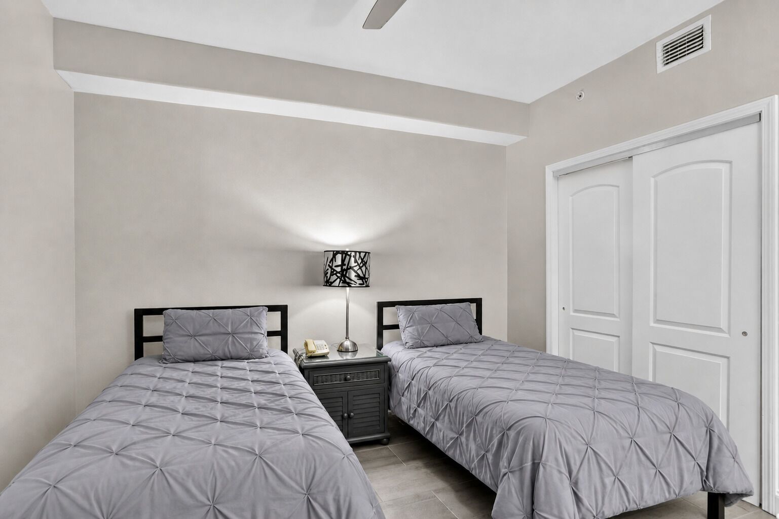 Une chambre avec deux lits, une table de chevet, une lampe et une armoire.