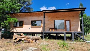 A modern wooden cabin with large windows, a deck, and a natural surrounding. - Cabaña Aida Epuyén - comfortable and bright cabin in a natural setting (Epuyén)