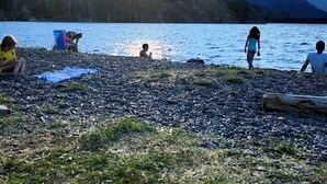 A pebbled beach with people relaxing and a mountain in the background. - Cabaña Aida Epuyén - comfortable and bright cabin in a natural setting (Epuyén)