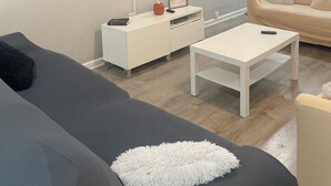 Un soggiorno moderno con una televisione a schermo piatto, un divano, un tavolino da caffè e una ventola a soffitto.