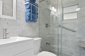 A modern bathroom with a glass-enclosed shower, a white sink, and a toilet. - BRAND NEW REMOLDED Bay Breeze On The Coast (Hernando Beach)