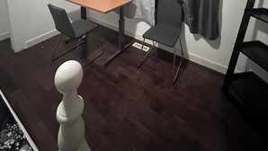 Et lille rum med et træbord og to stole, et vindue med grå gardiner og et mørkt trægulv.