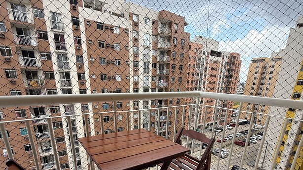 Ein Balkon mit Holztisch und -stühlen, mit Blick auf ein Wohngebiet und mehrstöckige Gebäude.
