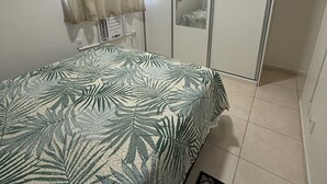 Ein Schlafzimmer mit einem Bett, einem Kleiderschrank, einem Spiegel und einem kleinen Teppich.
