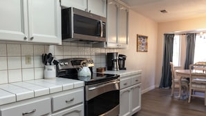 A modern kitchen with white cabinetry, a stainless steel oven, a microwave, and a coffee maker. - Moonrise Retreat, SPA, Near Yosemite & Bass Lake (Oakhurst)