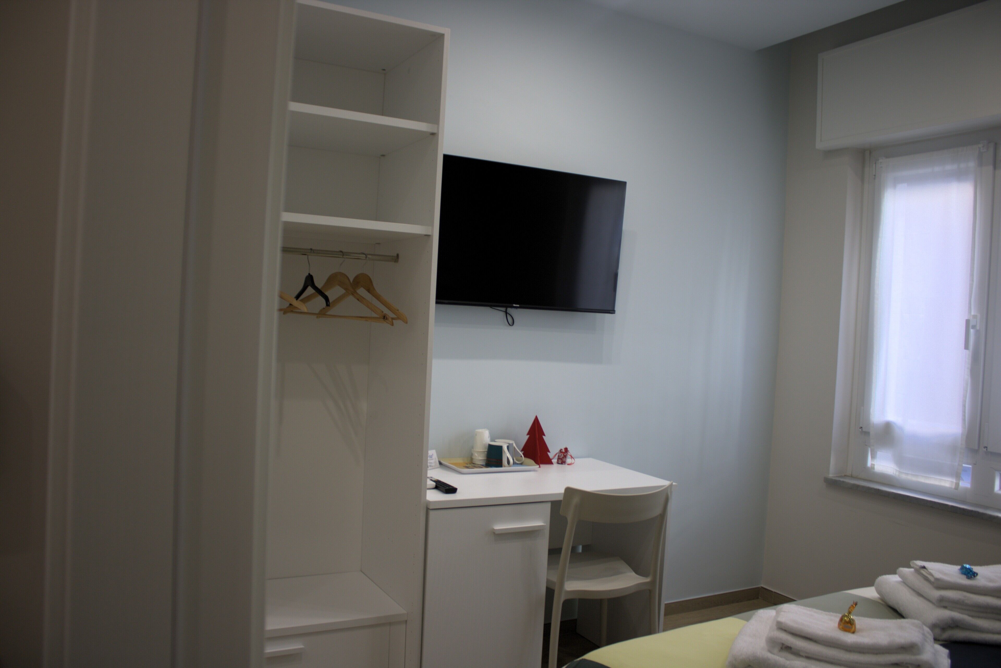 Una habitación con cama, escritorio, silla, televisor y armario.