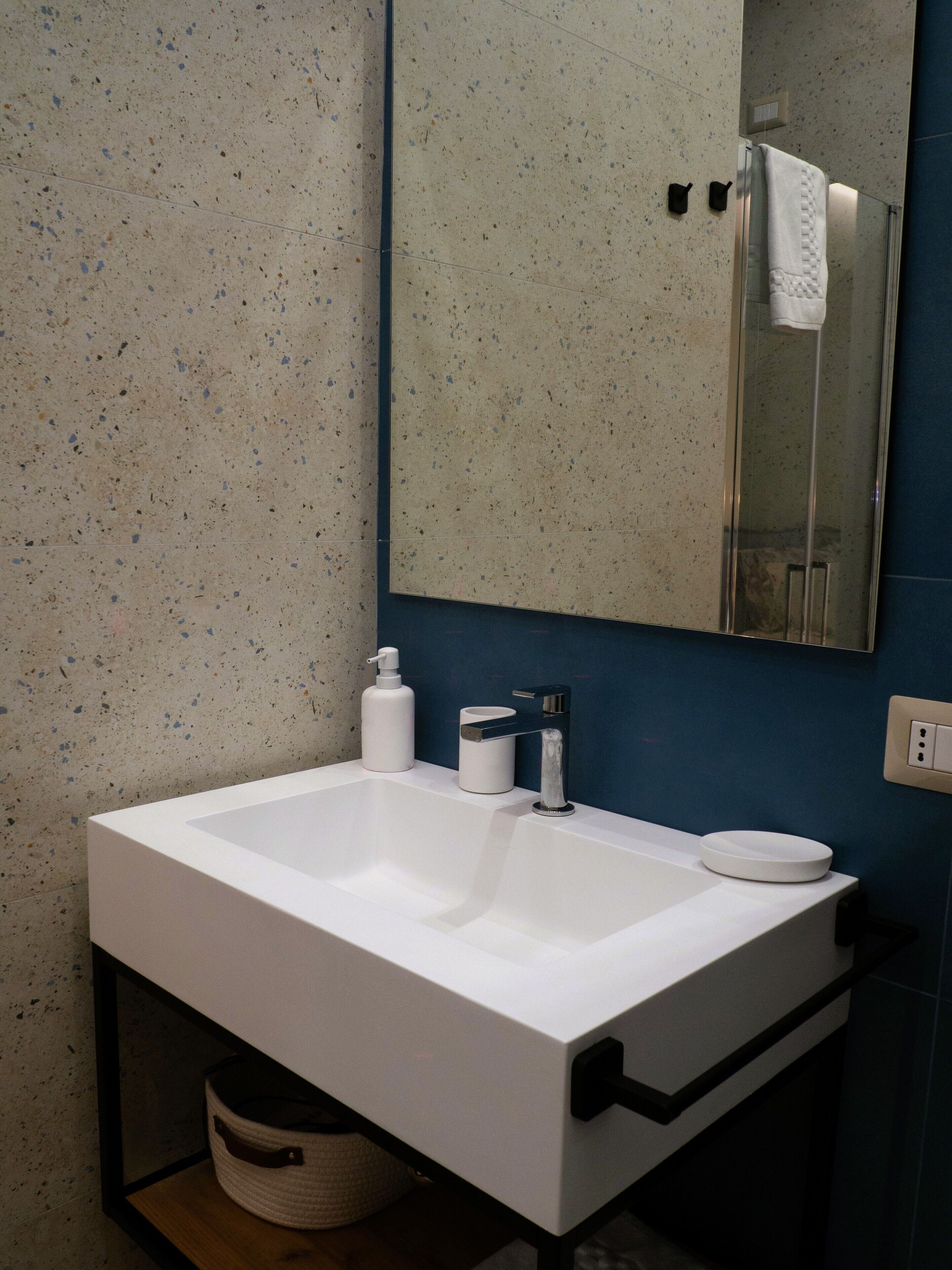 A bathroom with a white sink, a mirror, and a blue wall.