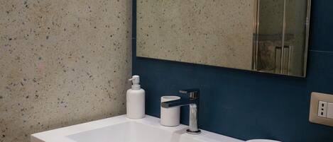 A bathroom with a white sink, a mirror, and a blue wall.