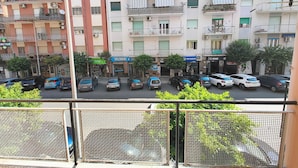 Un edificio residencial de varios pisos con balcones, autos estacionados y diferentes comercios.