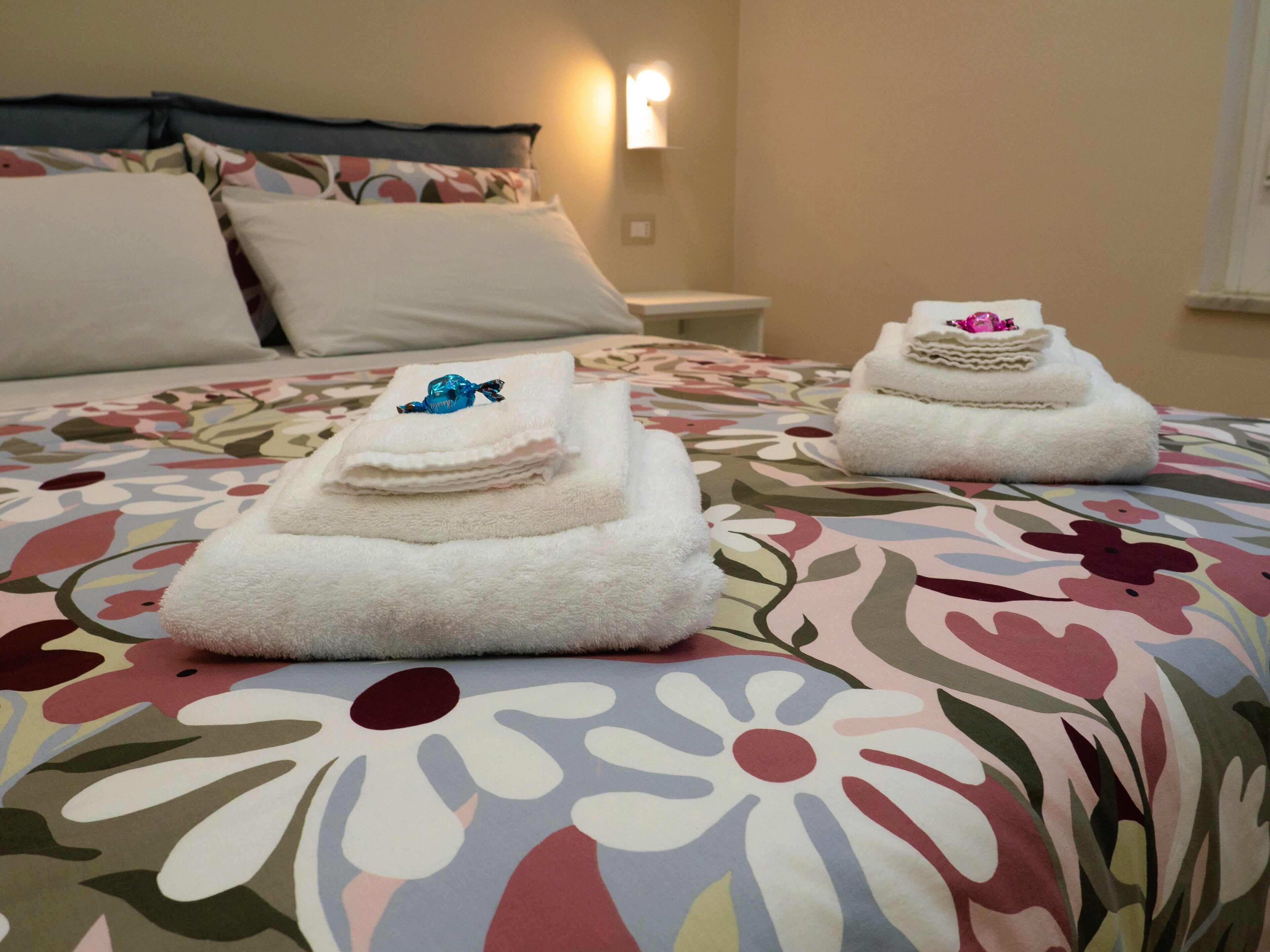 Cama com roupa de cama estampada e duas toalhas dobradas com um objeto decorativo em cima.