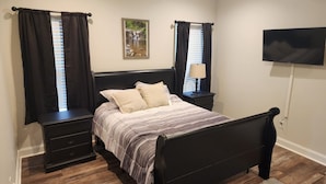 A bedroom with a bed, two nightstands, a TV, and a picture on the wall.