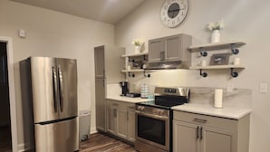 A modern kitchen with stainless steel appliances, wooden flooring, and built-in cabinetry.