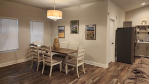 A dining area with a wooden table and chairs, a chandelier, and framed artwork on the walls.