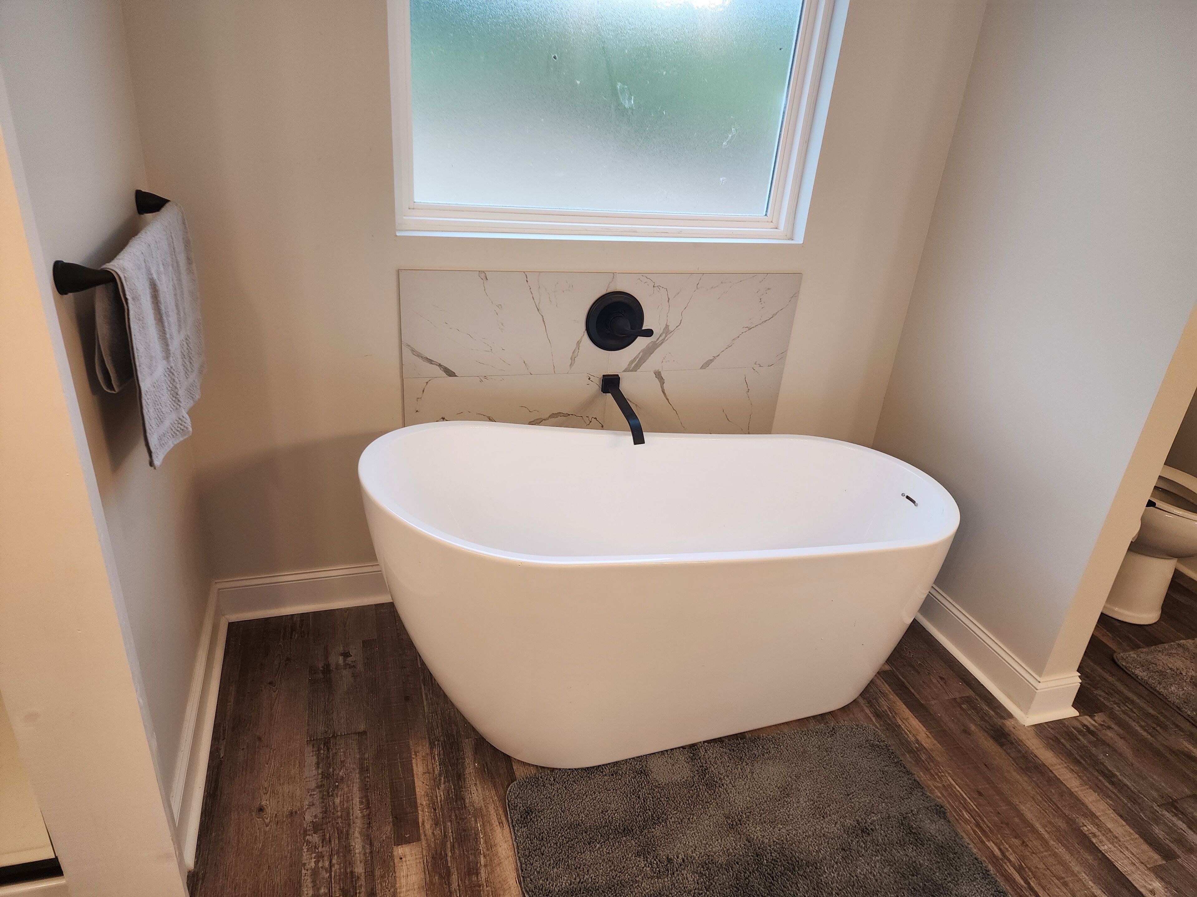 Une salle de bain avec une baignoire sur pieds, une fenêtre et un pare-baignoire en marbre.