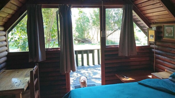 A cabin with a loft bedroom, a wooden deck, and a view of the outdoors. - Tannenhof Guest Farm (Tsitsikamma)