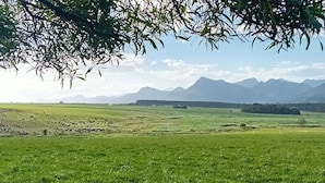 A wide, open field with a mountain range in the background. - Tannenhof Guest Farm (Tsitsikamma)