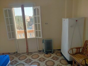A room with a patterned floor, a radiator, a white refrigerator, and a wooden chair. - A clean and sunny apartment in the heart of Siwa (Siwa Oasis)