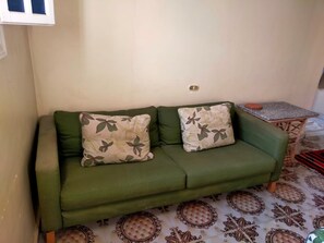 A green sofa with floral cushions in a room with patterned floor tiles. - A clean and sunny apartment in the heart of Siwa (Siwa Oasis)