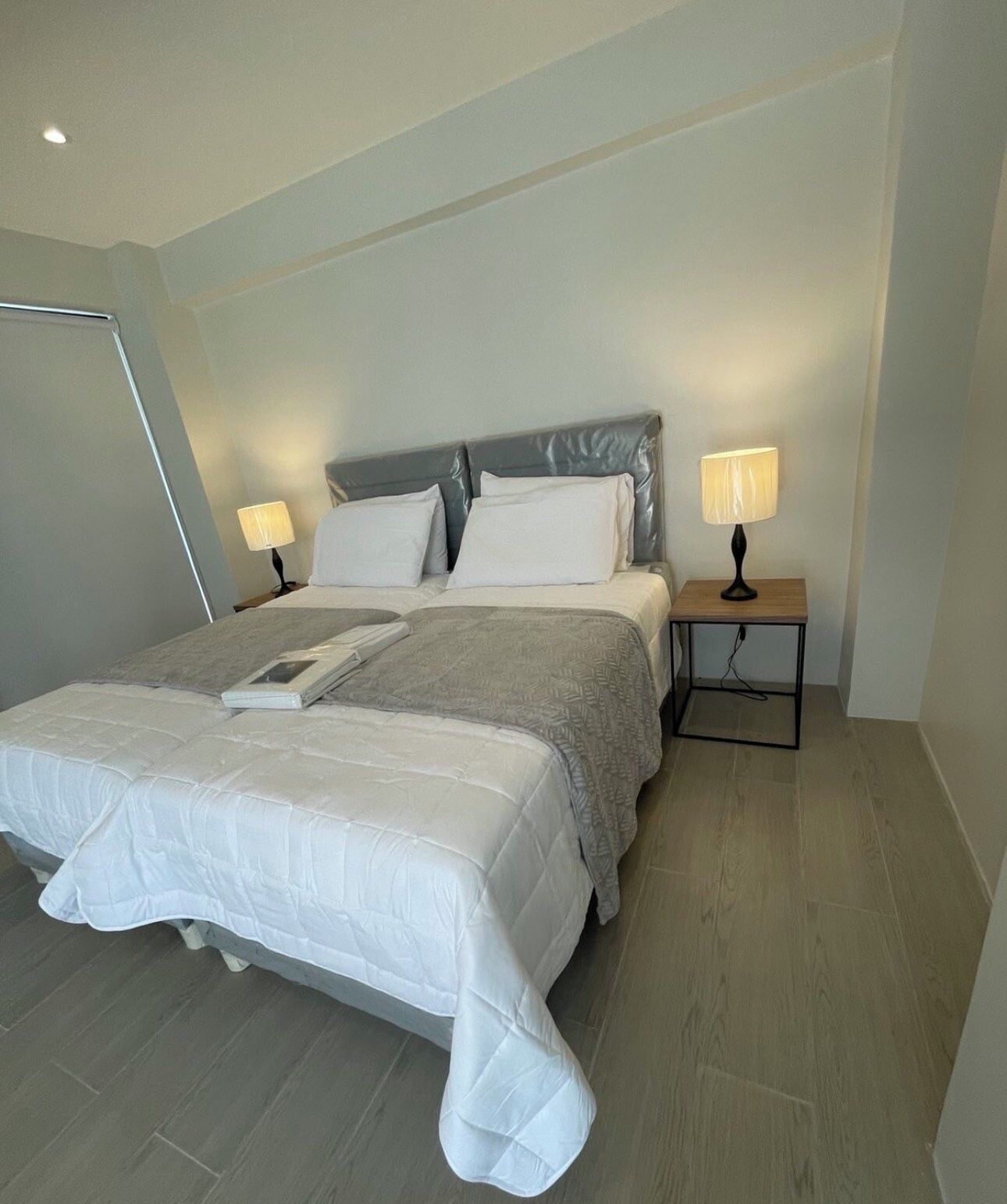 A neatly arranged bedroom with a bed, two bedside tables with lamps, and a slanted ceiling.