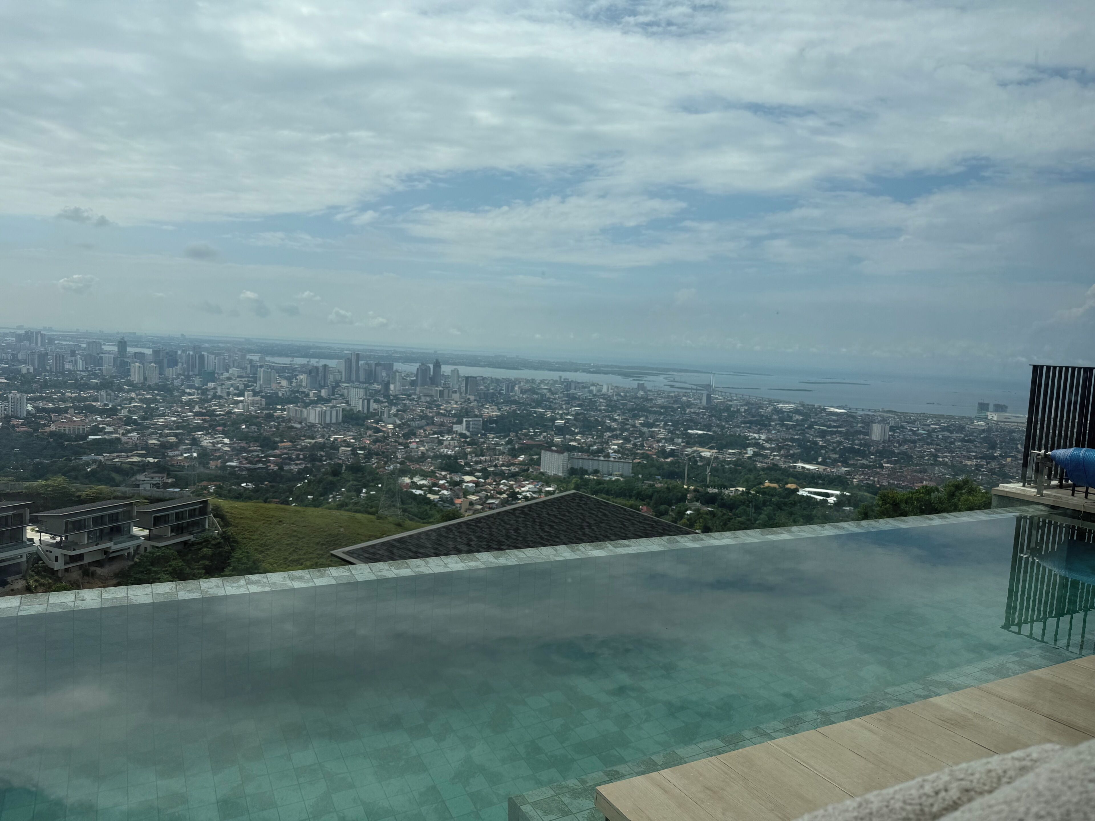 A cityscape view from a high vantage point, including a swimming pool with clear water.