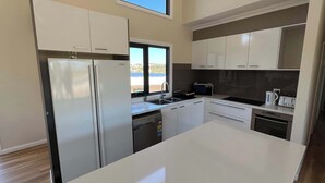 A modern kitchen with white cabinets, a built-in dishwasher, a stove, and a window overlooking a scenic view.