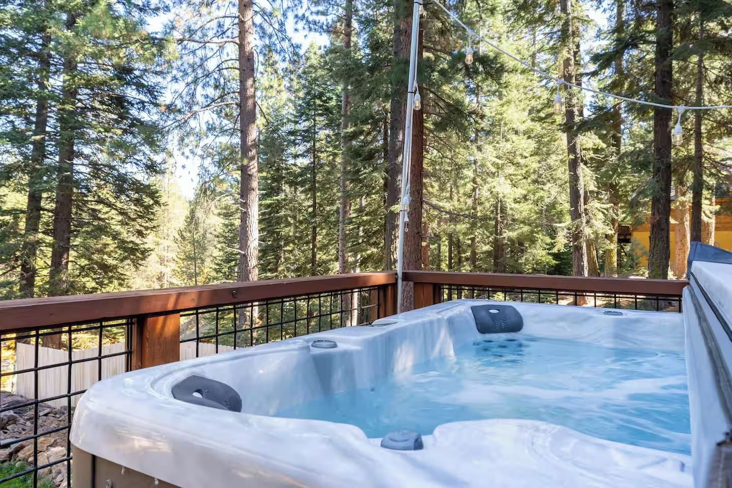 A hot tub on a deck surrounded by tall trees.