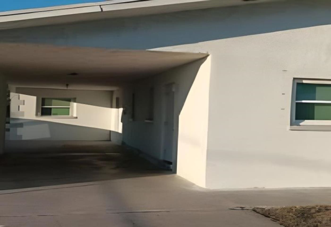 Un edificio moderno con zona de estacionamiento techada y una ventana lateral.