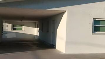 Un edificio moderno con zona de estacionamiento techada y una ventana lateral.