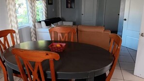 A dining area with a round table, wooden chairs, and a red fruit basket. - GpL 3115 B 3 Bed 1 Bath (Fort Myers)
