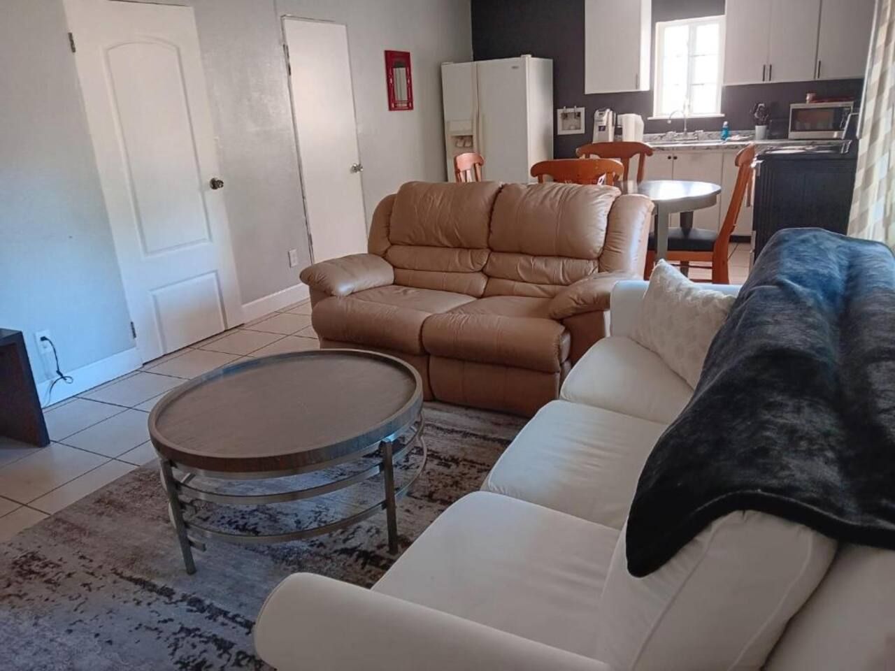 Un salon avec un canapé beige, une table basse ronde et un fauteuil inclinable marron.