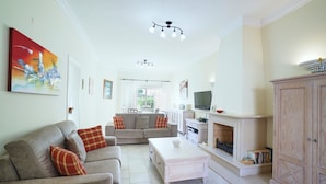 A spacious living room with a sofa set, a coffee table, a fireplace, and a television. - Villa sunset Solarenga is quiet villa w / private pool 10min from the beach (Lagoa)