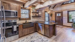 A modern kitchen with wooden cabinetry, stainless steel appliances, and a large island. - Woodland Cabin: Hot Tub, Deck & Game Loft (Sevierville)