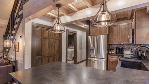 A kitchen with wooden cabinets, stainless steel appliances, and pendant lighting. - Woodland Cabin: Hot Tub, Deck & Game Loft (Sevierville)