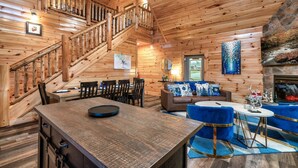 Ein Interieur einer Holzhütte mit Essbereich, einer Couch und einem Kamin.