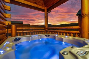 A hot tub with a digital control panel, surrounded by wooden logs and a wooden railing, overlooking a scenic landscape during sunset. - Private 84° Indoor Pool, 70" TV, Views, Hot Tub, Arcade, Air Hockey, 300mb WIFI (Pigeon Forge)