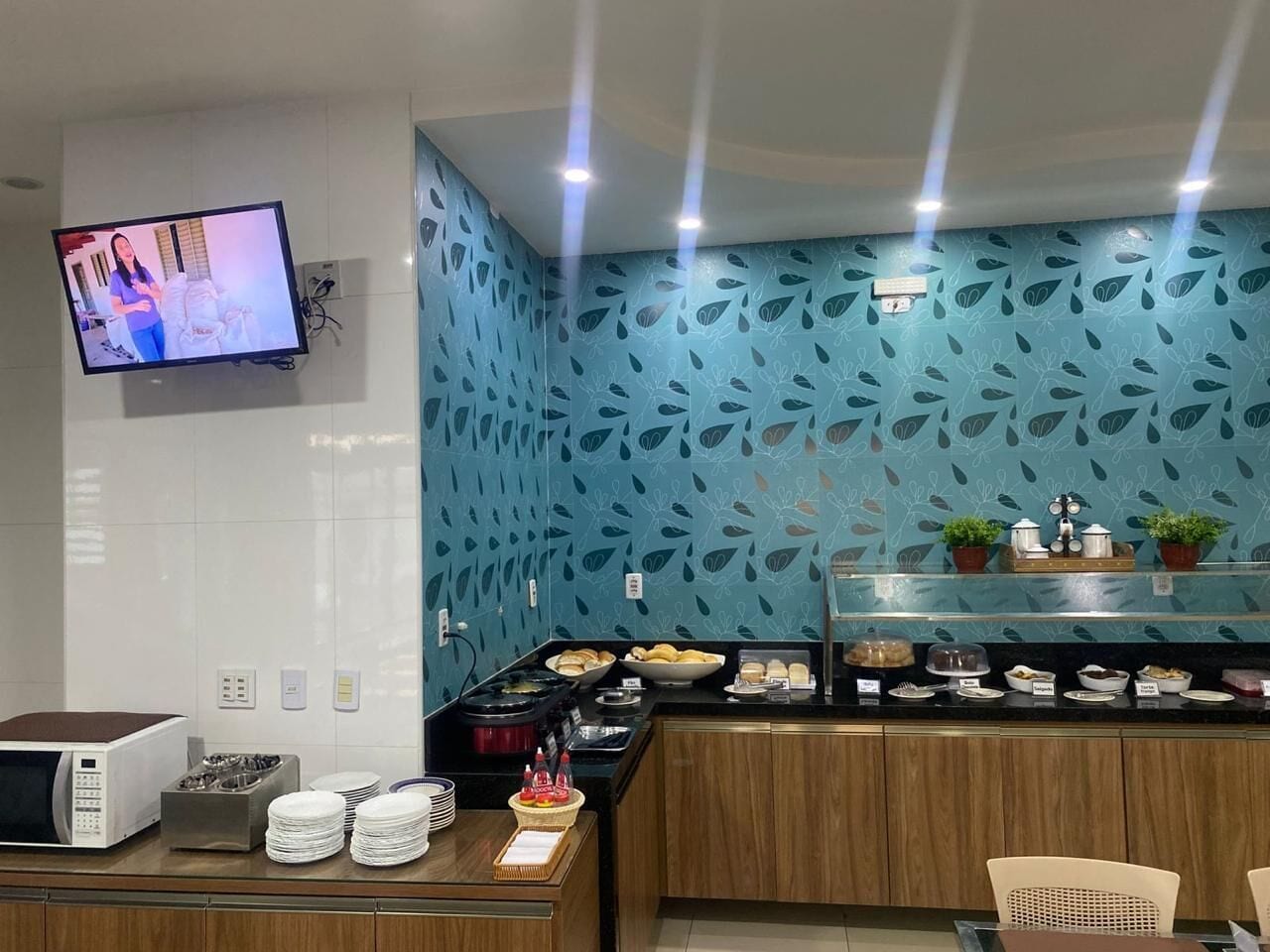 A breakfast area with a microwave, toaster, and stacked plates.