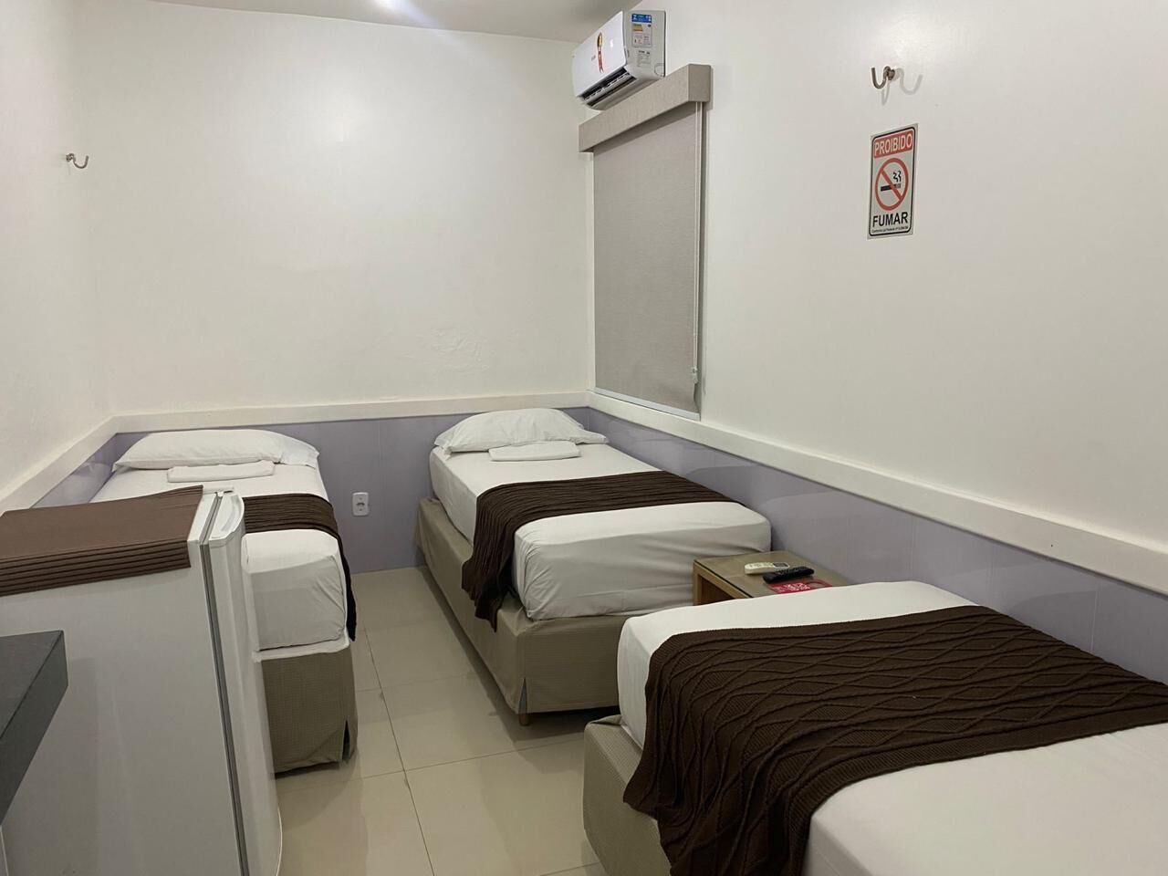 A small, clean room with three beds, a desk, and a window.