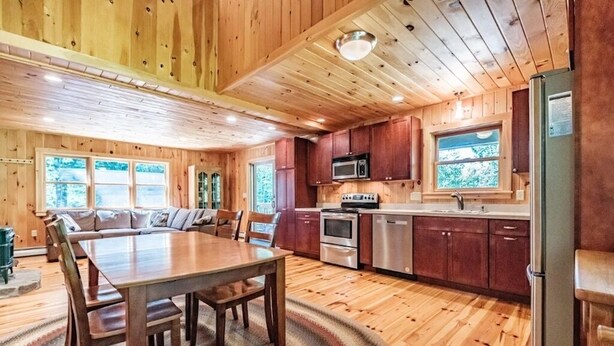 Interior de madera con comedor, cocina y ventanas amplias.