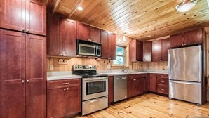 Una cocina con armarios de madera, electrodomésticos de acero inoxidable y suelo de madera.