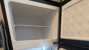 Un refrigerador abierto con varios estantes y un compartimento congelador.
