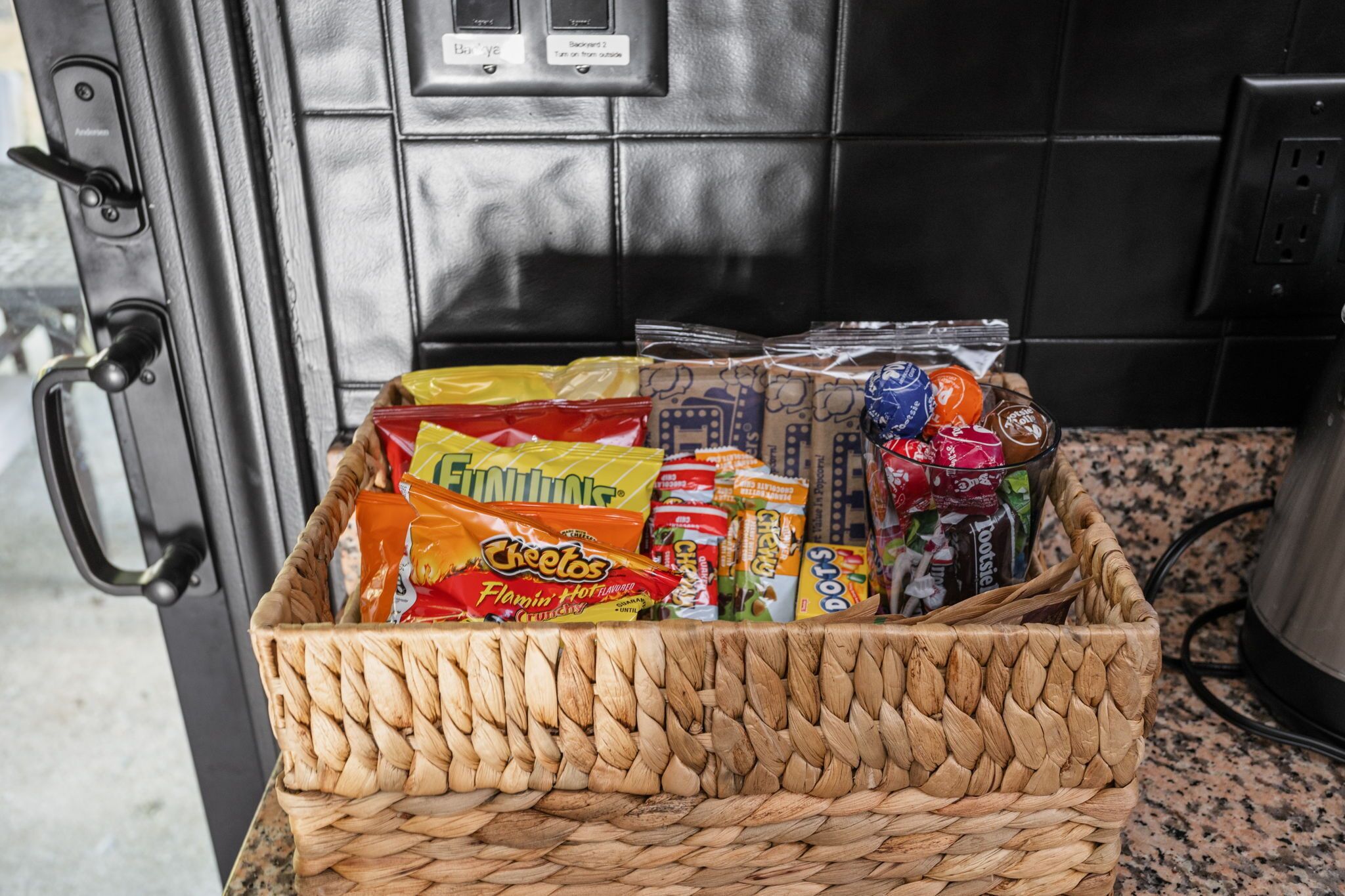 A wicker basket filled with various snacks and packaged goods on a kitchen counter.