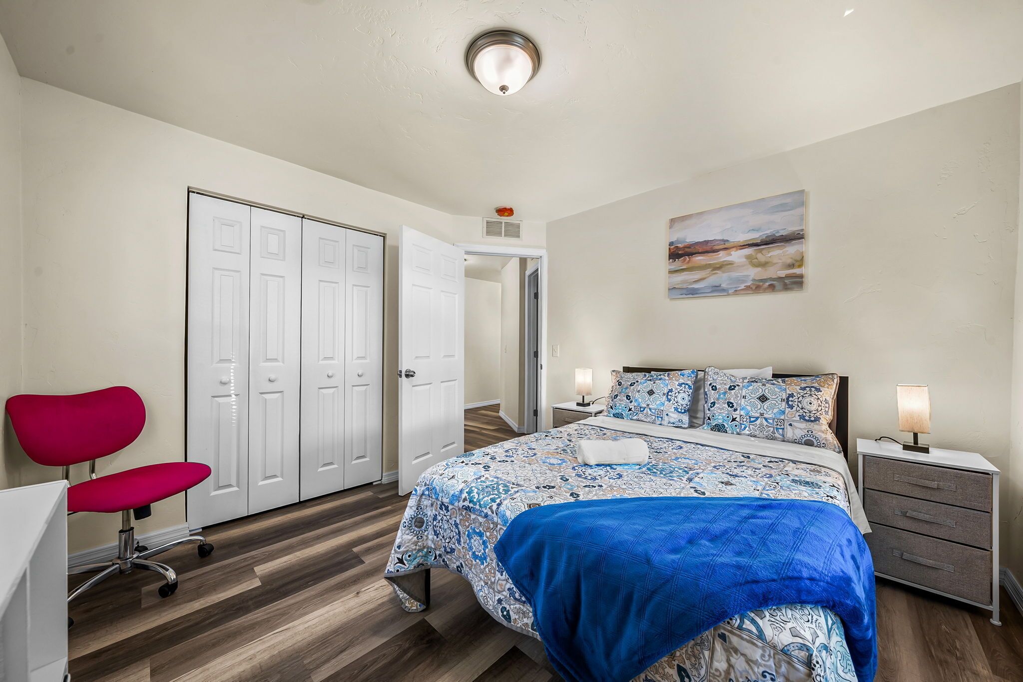 A bedroom with a bed, a desk, a chair, a wardrobe, and a nightstand.