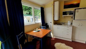 A compact kitchen with a dining table, white cabinets, a microwave, and a refrigerator.