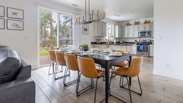 A modern kitchen with white cabinets, stainless steel appliances, and a dining area with a black table and brown chairs. - 5BR Flagstaff Forest Home Mountain Retreat (Flagstaff)