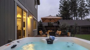A hot tub in a backyard with a patio area, outdoor furniture, and a large umbrella. - 5BR Flagstaff Forest Home Mountain Retreat (Flagstaff)