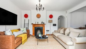 Un salon avec une cheminée, deux canapés, une table basse et un téléviseur.