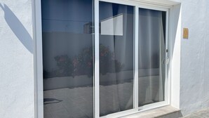 Eine Glastür mit weißem Rahmen, die zu einer gefliesten Terrasse führt.