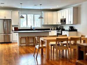 Une cuisine moderne avec des meubles blancs, des appareils en acier inoxydable et un plancher en bois.