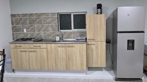 Una cuina moderna amb fogó de gas integrat, un rentapeus d'acer inoxidable, armaris de fusta i un frigorífic blanc.